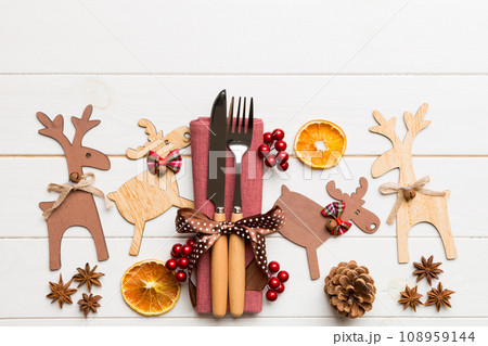 New year set of fork and knife on napkin. Top view of christmas decorations and reindeer on wooden background. Holiday family dinner concept with empty space for your design 108959144