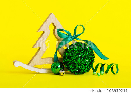 Christmas ball with decorative wooden tree on colored background. decoration bauble with ribbon bow with copy space Christmas ball with decorative wooden tree on colored background. decoration bauble with ribbon bow with copy space 108959211
