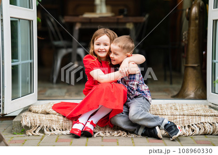 Cute and happy brother and sister sitting on the porch of a country house.  Cute and happy brother and sister sitting on the porch of a country house.  108960330
