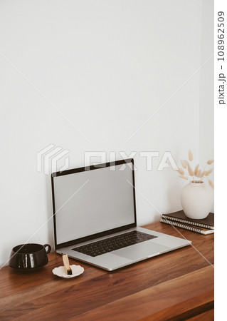 Laptop with blank screen on wooden table in home interior. Workplace mockup concept Laptop with blank screen on wooden table in home interior. Workplace mockup concept 108962509