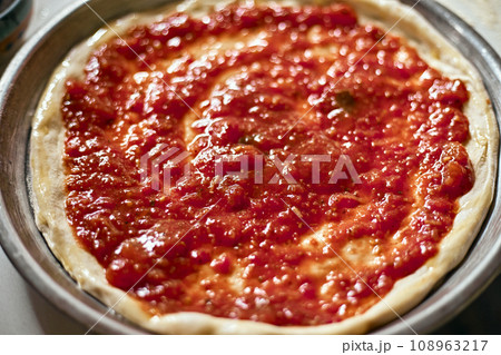 Spreading tomato sauce on pizza pan Spreading tomato sauce on pizza pan 108963217