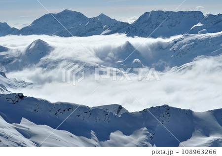Snow covered high mountains, fog and clouds raising from above Snow covered high mountains, fog and clouds raising from above 108963266