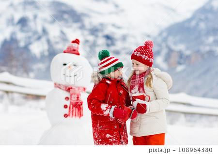 Child building snowman. Kids build snow man. Child building snowman. Kids build snow man. 108964380