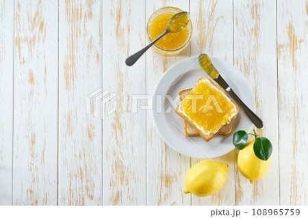 Plate with toast and sweet lemon jam on light wooden table, top view. Plate with toast and sweet lemon jam on light wooden table, top view. 108965759