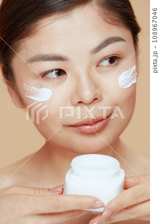 young woman with facial cream jar and facial cream on face 108967046