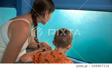 Mother with little son exploring underwater sea world and fishes while traveling on tourist submarine. Holiday, summer vacation and tourism 108967118