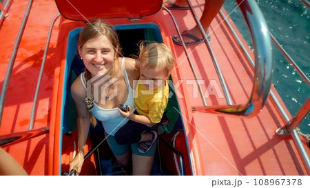 Happy smiling woman with baby son walking up the stairs on tourist submarine. Family holiday, summer vacation and tourism 108967378