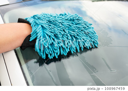 A man washes the car windshield with a large blue washcloth. Car wash, self-service. A man washes the car windshield with a large blue washcloth. Car wash, self-service. 108967459