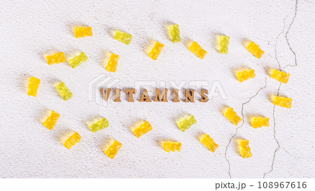 The word vitamins from letters and gummy vitamins in the form of candy bears around top view The word vitamins from letters and gummy vitamins in the form of candy bears around top view 108967616