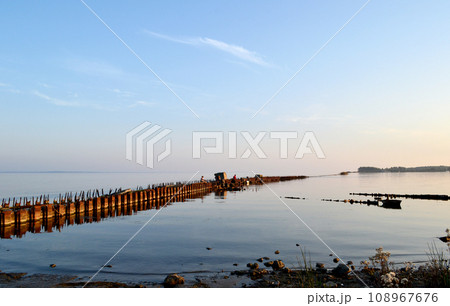 old wooden pier on the Baltic spit, Baltiysk, Kaliningrad region, fishermen at sunset 108967676
