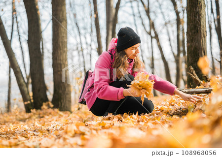 Young woman in a hat collects autumn leaves. Fall season concept. Generation Z and gen z youth 108968056