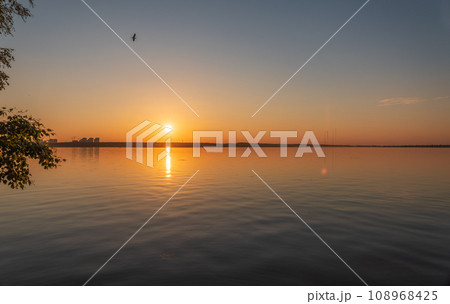 Lake with pine and birch forest on the shores at summer or early autumn sunset. Lake with pine and birch forest on the shores at summer or early autumn sunset. 108968425