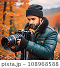 A dark-skinned male photographer with a beard in a hat and a winter jacket. 108968588
