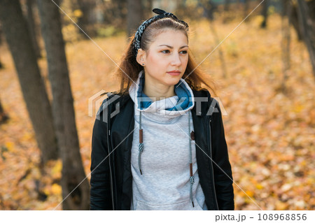 Outdoor atmospheric lifestyle portrait of young beautiful young woman. Warm autumn fall season 108968856
