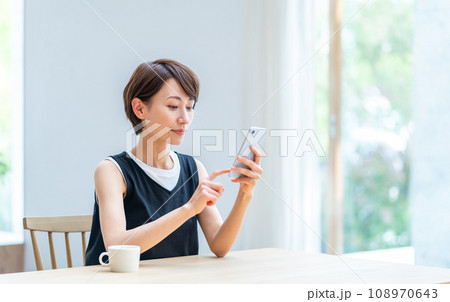 リビングでスマホを操作する女性。 リビングでスマホを操作する女性。 108970643