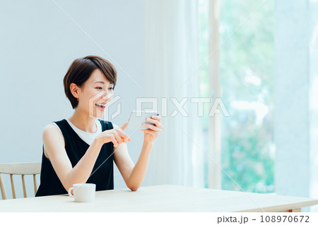 リビングでスマホを操作する女性。 108970672