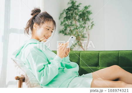 部屋着でスマホを使う女性 108974321