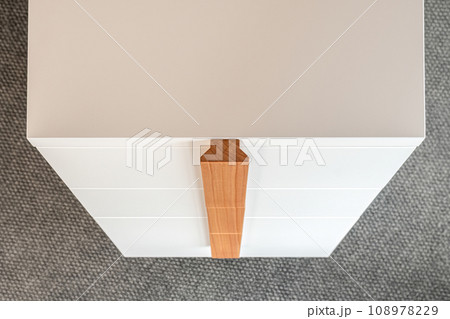 Minimalist white office chest of drawers with natural wooden brown handles and legs closeup view. Stylish furniture model 108978229
