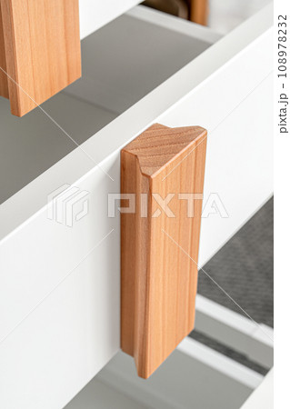 Stylish white office commode with wooden handles and legs with open empty drawers closeup view. Comfortable furniture for home and office furnishing 108978232