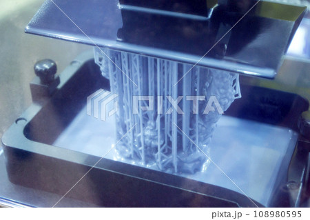Working of photopolymer sla 3D printer. Platform with building object lowered into liquid photopolymer resins and hardened under ultraviolet laser. Progressive additive technology. 3D printer printing 108980595