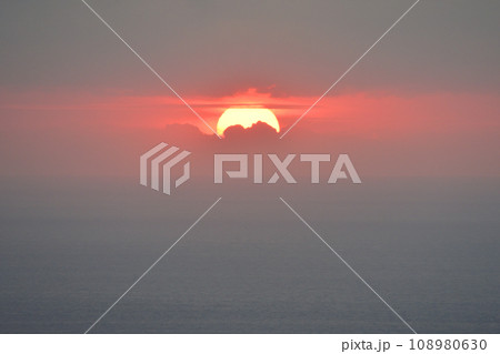 曇り空の中で海に沈んでいく夕日 曇り空の中で海に沈んでいく夕日 108980630