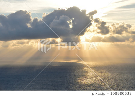 曇り空の中で海に沈んでいく夕日 108980635
