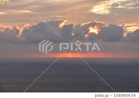 曇り空の中で海に沈んでいく夕日 108980639