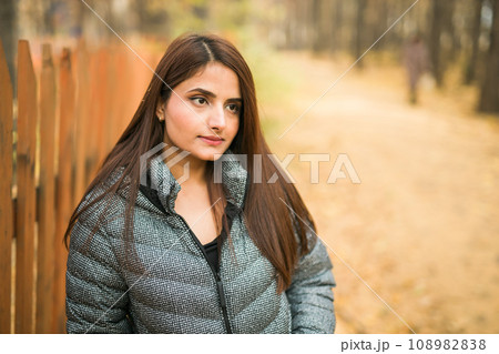 Beautiful indian woman generation z relaxing and feeling nature at autumn park in fall season copy space. Diversity and gen z youth 108982838