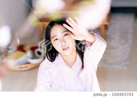 桜の花に手を伸ばす若い女性 108983703
