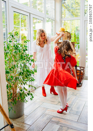 Mother and daughter in a room dancing in elegant dresses Mother and daughter in a room dancing in elegant dresses 108983797