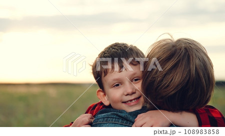 Son running with loud laugh to mother to comforting with hug on grass field Son running with loud laugh to mother to comforting with hug on grass field 108983858