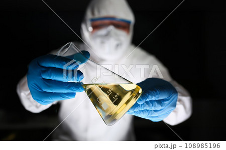 Male chemist look at microscope hold test tube Male chemist look at microscope hold test tube 108985196