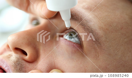 Man putting liquid drops in his eye solving vision problem 108985240