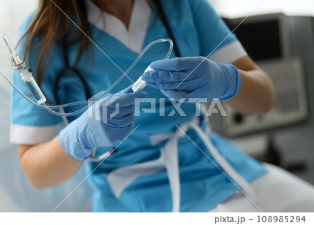 Female nurse hand in blue protective gloves hold dropper 108985294