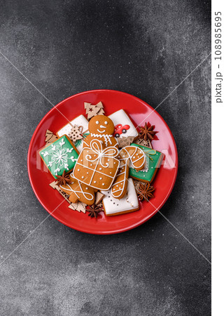 Beautiful delicious sweet winter Christmas gingerbread cookies on a gray textured background Beautiful delicious sweet winter Christmas gingerbread cookies on a gray textured background 108985695