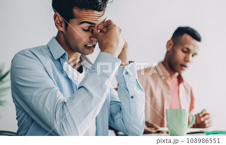 Stressful male employee feeling tired from deadline in office company exhausted at desktop Stressful male employee feeling tired from deadline in office company exhausted at desktop 108986551