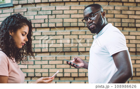 Male and female hipsters walking outdoors holding smartphones ignore real life 108986626