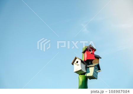 Wooden small bird houses and birdhouses against the blue sky. Real estate and affordable housing concept. Mortgage, loan, taxes. Buying, selling and renting apartments. Copy space Wooden small bird houses and birdhouses against the blue sky. Real estate and affordable housing concept. Mortgage, loan, taxes. Buying, selling and renting apartments. Copy space 108987084