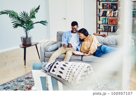 happy couple in love watching funny video on mobile phone and laughing in apartment 108987107