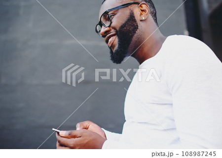 happy smiling hipster guy with cellphone enjoying time on publicity area 108987245