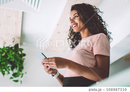 Young smiling female standing with smartphone device in hands Young smiling female standing with smartphone device in hands 108987310