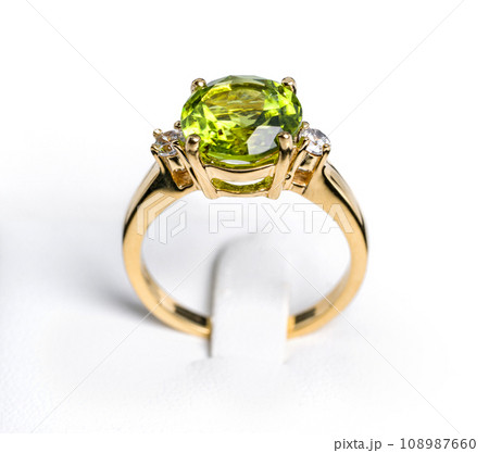 A vibrant peridot gemstone graces the center of a glossy, tarnish-resistant, yellow gold ring. The ring is accented with multiple pave-set  diamonds, sparkling exquisitely to complement the main stone 108987660