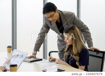 Multiple business people are gathered at a table, discussing business in a professional conference room. Multiple business people are gathered at a table, discussing business in a professional conference room. 108987879