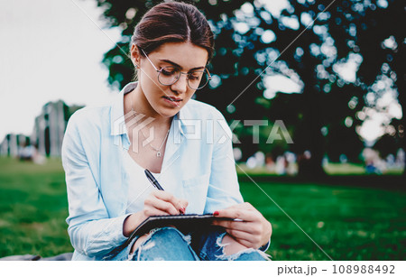 Smart hipster student sitting on green grass Smart hipster student sitting on green grass 108988492