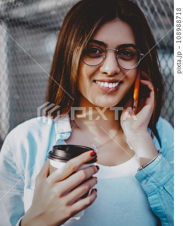 Cute female blogger talking on mobile phone Cute female blogger talking on mobile phone 108988718