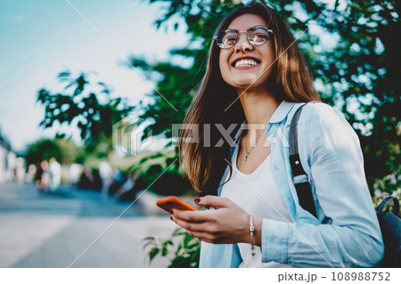 Positive hipster girl with backpack having fun outdoors in green park Positive hipster girl with backpack having fun outdoors in green park 108988752