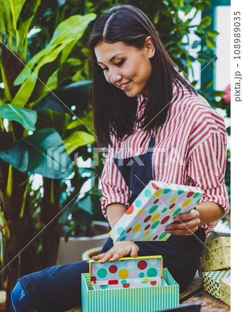 Positive asian woman in apron working in flower shop making decoration for presents 108989035