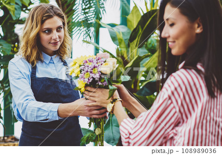 Professional female gardener selling fresh flowers from own botanic greenhouse 108989036