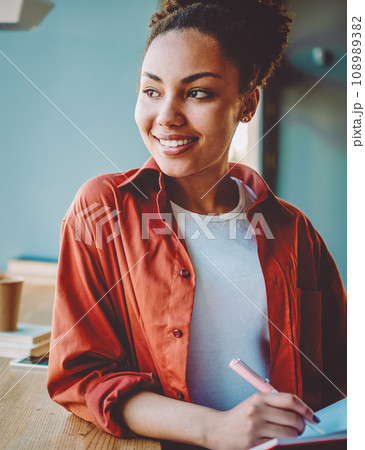 happy dark skinned woman holding textbook for education 108989382