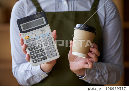 コーヒーと電卓を持つカフェ店員 コーヒーと電卓を持つカフェ店員 108989537